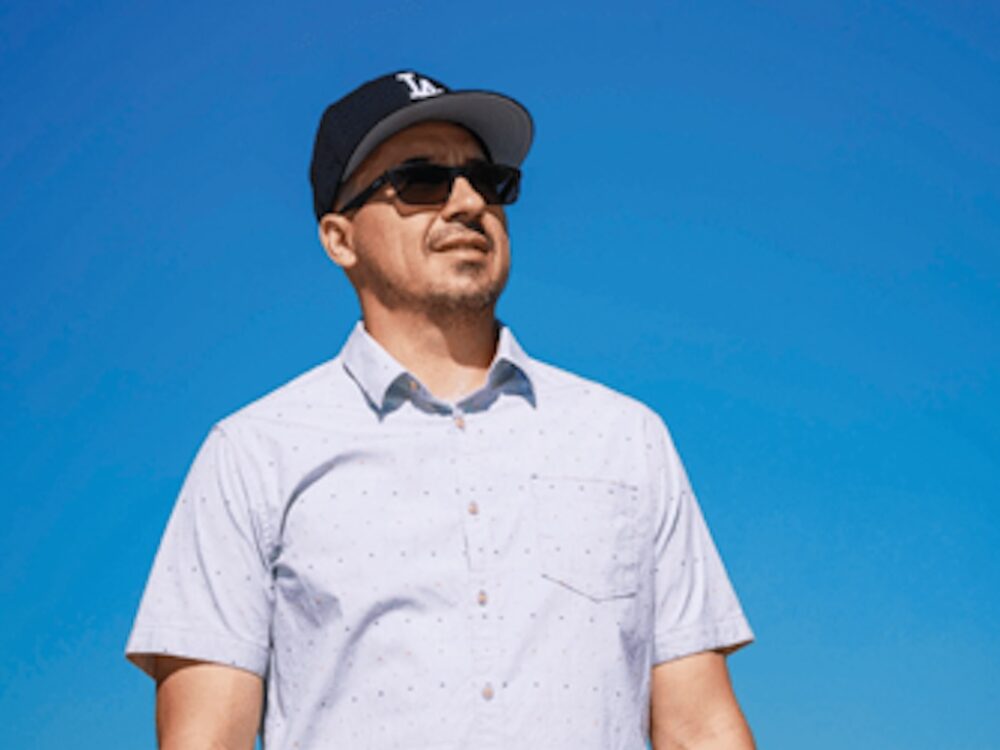 Man in sunglasses and cap under blue sky, representing innovative solar-inspired LED lighting solutions for optimized crop yield in controlled environments by Fluence, Austin-based horticulture lighting experts.