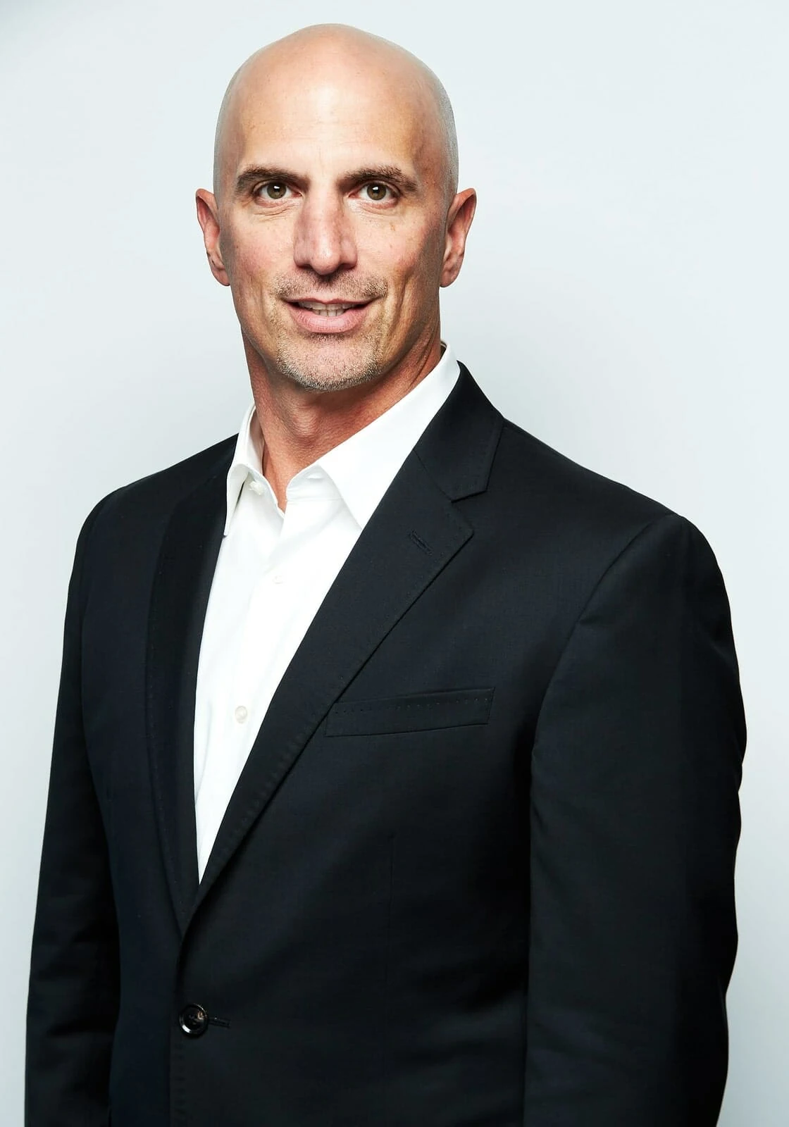Bald man in suit with cannabis LED grow lights, commercial cultivation setting.