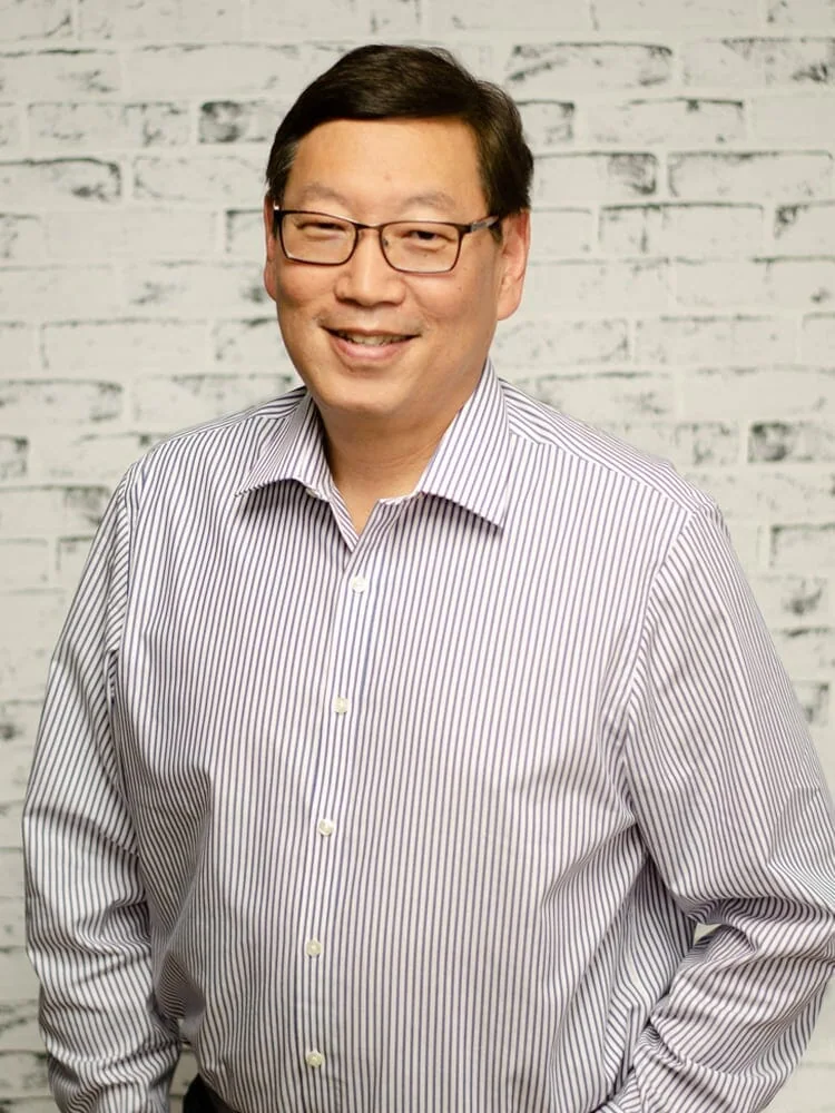 Smiling man in glasses with striped shirt, expert in cannabis lighting technology.