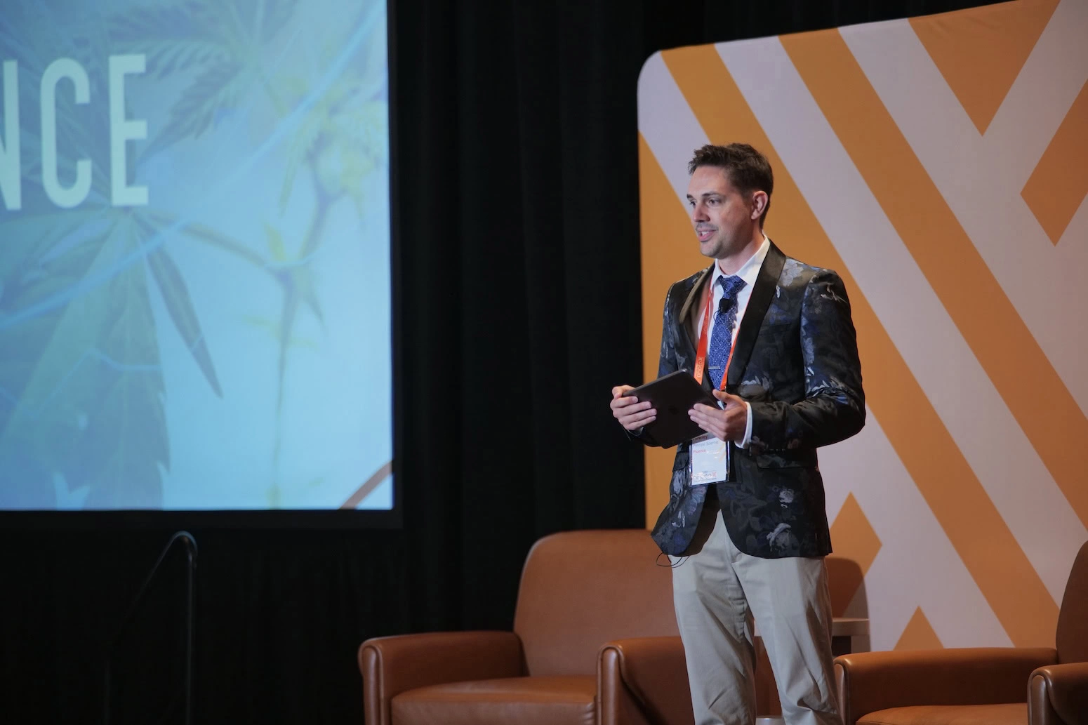 A man in a suit presents cannabis lighting technology at a cultivation conference.