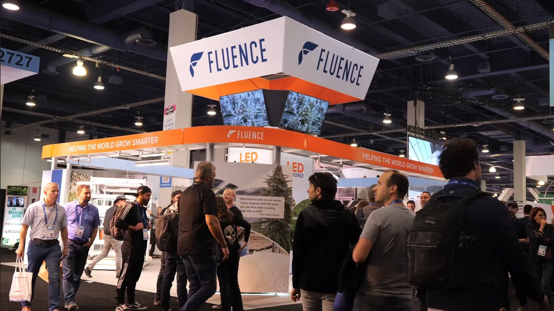 Visitors explore Fluence booth showcasing LED grow lights for commercial cannabis cultivation.