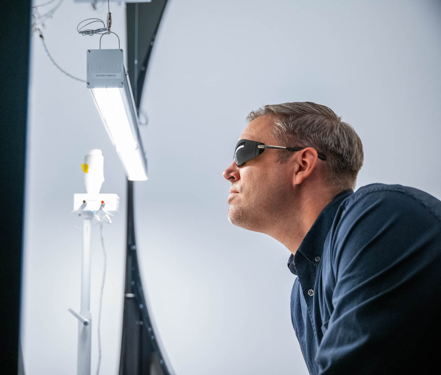 A man examines LED grow lights for cannabis in a commercial cultivation facility.