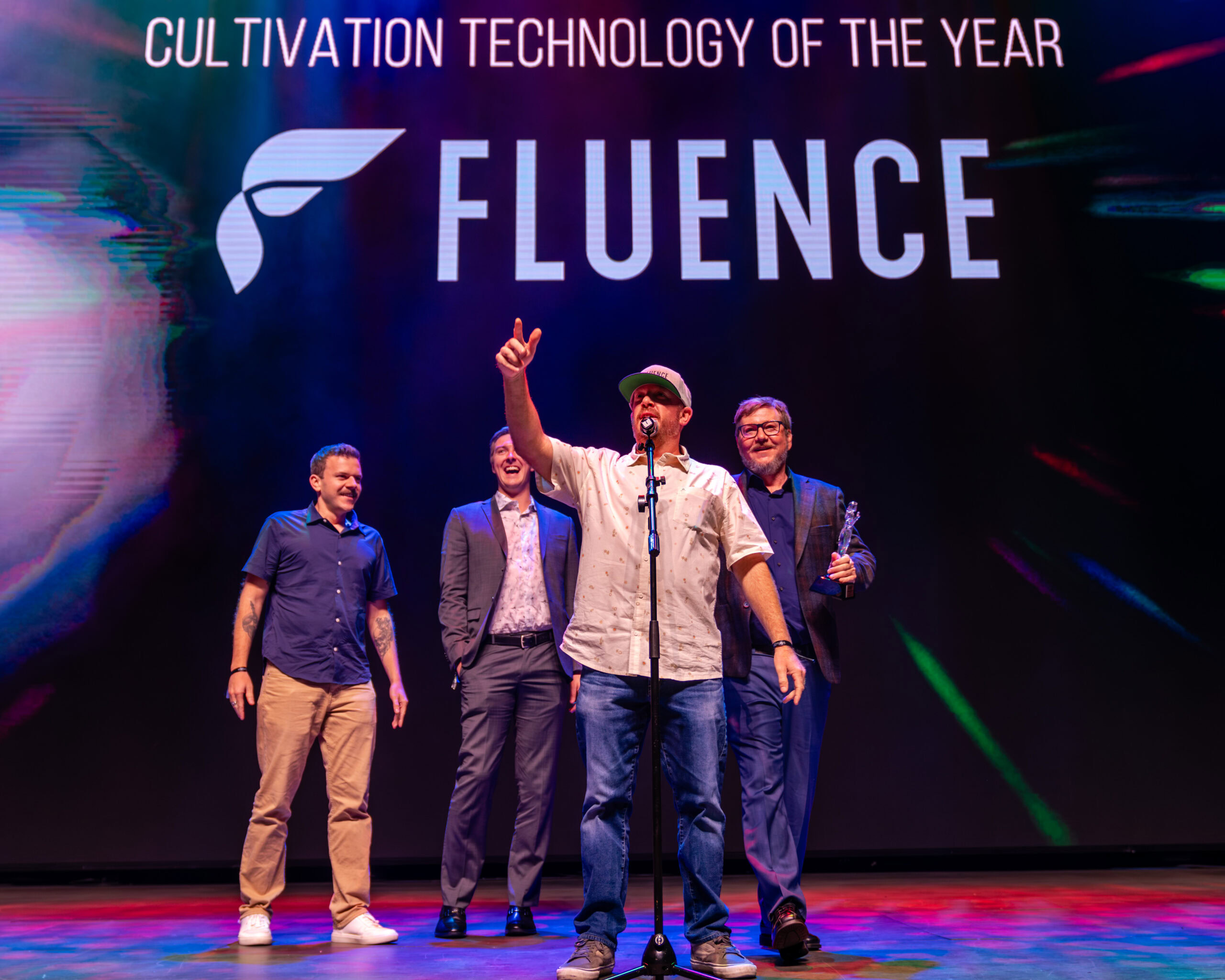 Four people accept the "Cultivation Technology of the Year" award for Fluence, an Austin-based LED lighting innovator enhancing crop yield and cannabis growth. One speaks into a microphone on stage.