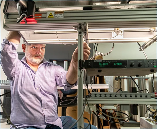 A technician adjusts LED grow lights for cannabis on a rack in a Fluence lab.